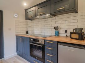 A kitchen with cabinets, sink, cooktop, oven, and refrigerator at Little Poppes Lawn, Holditch near Hawkchurch