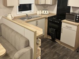 A kitchen with stove, sink, and seating area at 169 Abergele