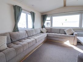 A living room with a sectional sofa and windows at St Michaels Caravan Park - 236 Towyn