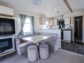 A kitchen area with a table and chairs at St Michaels Caravan Park - 236 Towyn