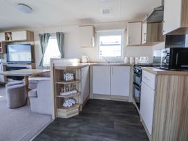 A kitchen with cabinets, sink, and dining area at St Michaels Caravan Park - 236 Towyn
