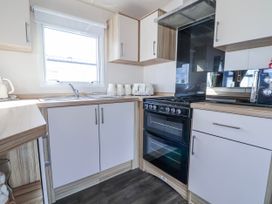 A kitchen with oven, sink, toaster and microwave at St Michaels Caravan Park - 236 Towyn