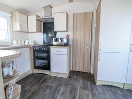 A kitchen with cabinets and appliances at St Michaels Caravan Park - 236 Towyn