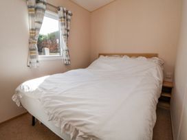 A bedroom with a bed and a window at St Michaels Caravan Park - 236 Towyn