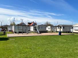 An outdoor area with playground equipment and caravans at The Beachside Hideout - St Michaels and Browns Caravan Park in Towyn