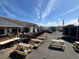 An outdoor seating area with benches and umbrellas at The Beachside Hideout - St Michaels and Browns Caravan Park Towyn