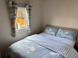 A bedroom with a bed and window at The Beachside Hideout - St Michaels and Browns Caravan Park, Towyn