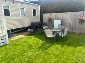 A garden with a table and chairs at The Beachside Hideout - St Michaels and Browns Caravan Park in Towyn