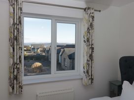 A window with curtains and a radiator in a bedroom at 27 Oversands View
