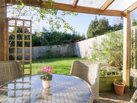 A garden with a table and chairs under a pergola at 27 Oversands View