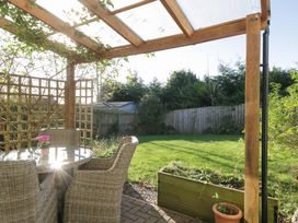 A garden with a table and chairs under a pergola at 27 Oversands View