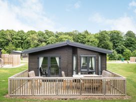 A cabin with a deck and seating area at Brayford Lodge (Pet) Louth