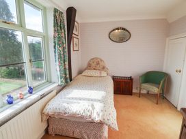 A bedroom with a bed and chair at the Farmhouse in Beccles