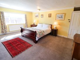 A bedroom with a bed, nightstand, and window at Winston Hall in Beccles