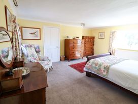 A bedroom with a bed, dresser, and chair at Winston Hall in Beccles