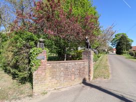 A brick wall with a gate and statues at Winston Hall in Beccles