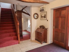 A hallway with a staircase and wooden chest of drawers at Winston Lodge in Beccles