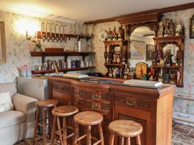A home bar with stools and shelves displaying decorative items at Winston Lodge in Beccles