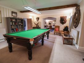 A snooker table with a bookshelf and armchair at Winston Lodge in Beccles