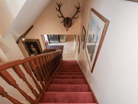 A staircase leading to a hallway with a deer head mount at Winston Lodge in Beccles