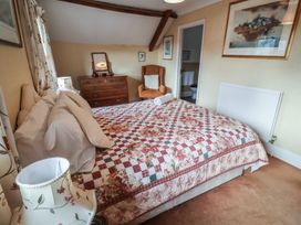 A bedroom with a bed, armchair, and dressing table at Winston Lodge in Beccles