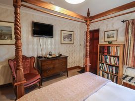A bedroom with a bed, armchair, dresser, and bookshelf at The Gun Room in Beccles
