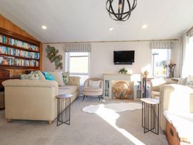 A living room with a sofa, armchair, and bookshelf at FW4 (Fairways 4)