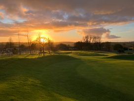 A sunset over a golf course with trees and hills at FW4 (Fairways 4) Doublebois near Dobwalls