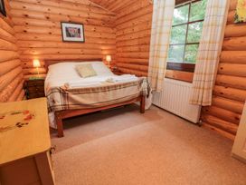 A bedroom with a bed and nightstands at Little Bears Hideaway @ 23 Lakeside Felmoor Park near Felton