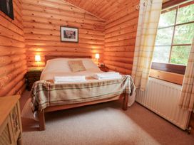 A bedroom with a bed, bedside table, and window at Little Bears Hideaway @ 23 Lakeside, Felmoor Park near Felton