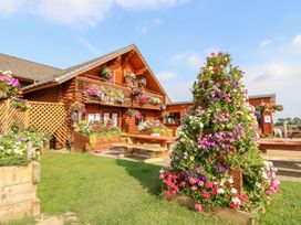 An outdoor area with a wooden building and flower decorations at Little Bears Hideaway @ 23 Lakeside in Felmoor Park near Felton