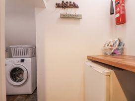 A laundry room with a washing machine and fridge at The Stables in Prestatyn