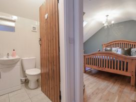 A bathroom with a toilet and sink adjoining a bedroom with a wooden bed at The Stables in Prestatyn
