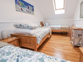 A bedroom with three beds and a painting at The Stables in Prestatyn