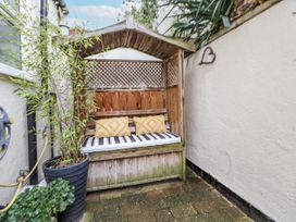 A garden seating area with a wooden bench and cushions at The Stables in Prestatyn