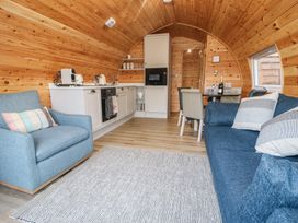 A living room with a sofa and kitchen area at Park View Lodge