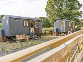 Two shepherd's huts with benches in an outdoor area at No 1 The Orchard Upton Warren