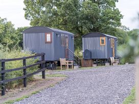 Two shepherd's huts with benches along the path at No 1 The Orchard, Upton Warren