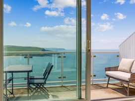 A balcony with a table and chairs overlooking the water at 6 Avon Quillet Bigbury-On-Sea