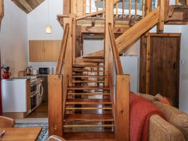 A living room with a staircase and kitchen area at Swallows Nest in Widecombe-in-the-Moor near Postbridge
