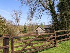 A wooden gate in front of stone and wooden houses with trees at Swallows Nest near Widecombe-in-the-Moor