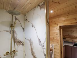 A shower with marble wall and wooden features at The Sty in Hatton, Derbyshire