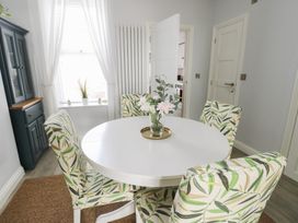 A dining room with a round table and floral chairs at Bryn Y Mor Beaumaris