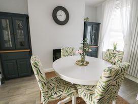 A dining room with a round table and patterned chairs at Bryn Y Mor in Beaumaris