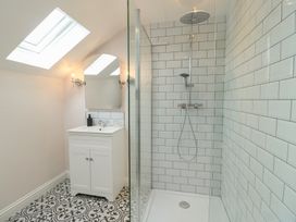 A bathroom with a shower, sink, and mirror at Bryn Y Mor in Beaumaris