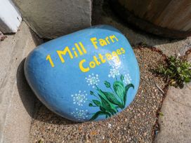 A painted stone with the text 1 Mill Farm Cottages and flowers at 1 Mill Farm Cottages Narberth
