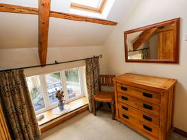A bedroom with a dresser, chair, and window at 1 Mill Farm Cottages in Narberth