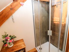 A bathroom with a shower enclosure and a wooden shelf at 1 Mill Farm Cottages Narberth
