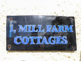 A sign displaying 1 Mill Farm Cottages in Narberth