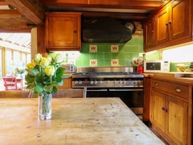 A kitchen with a stove, microwave, and flowers on a table at Town Farm